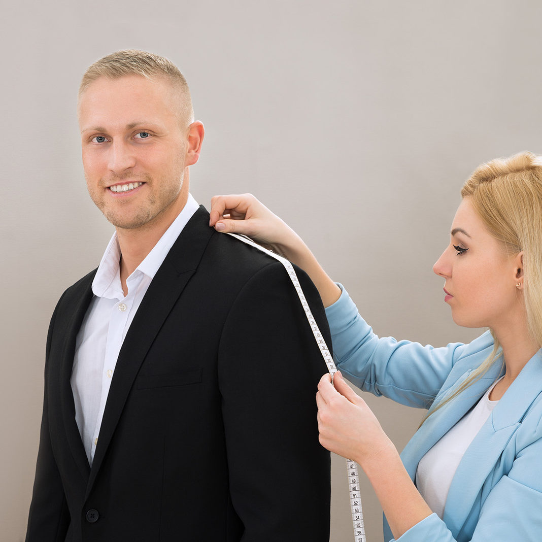 Young Female Tailor Takes Measures Of Man With Measuring Tape